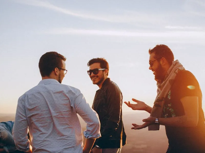 Três amigos conversando ao ar livre no fim da tarde